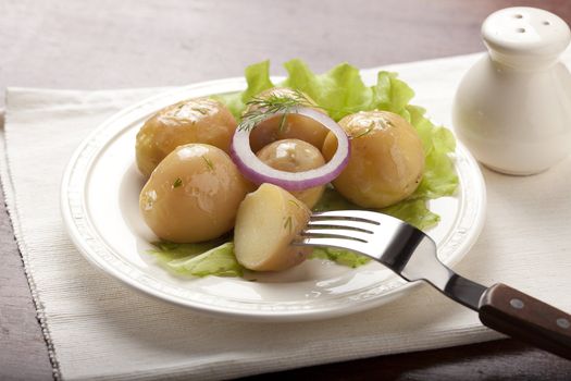 Boiled potato with onion and lettuce on the white plate