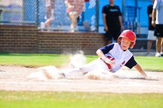 Youth baseball player sliding in at home.