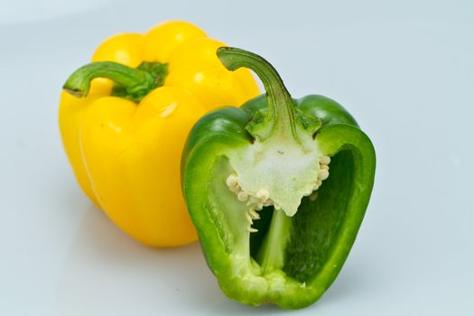 The yellow whole capsicum and cut green capsicum on bluish background