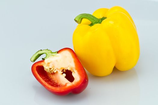The yellow whole capsicum and cut red capsicum on bluish background