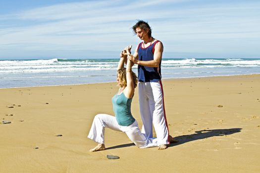 Yoga teacher teaches student yoga on the beach