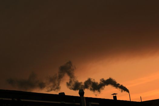 smoking chimney with a  warm orange sun
