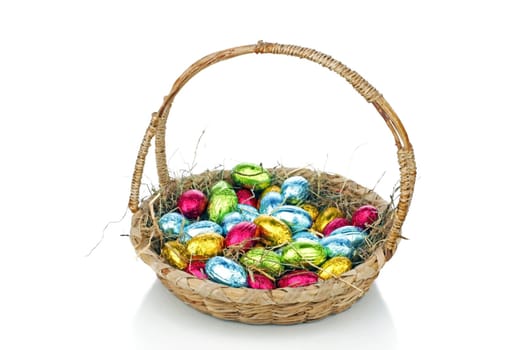 Little colored eggs in a basket with straw