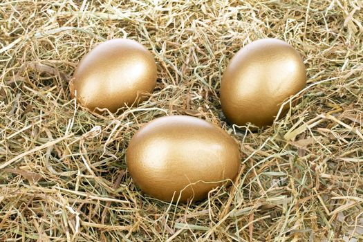 Three golden eggs in straw