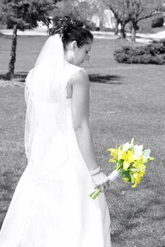 A bride looks at her flower bouquet in her hands.