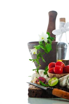 fresh vegetables and olive oil on an old weathered wood with a old mortar in behind over white background