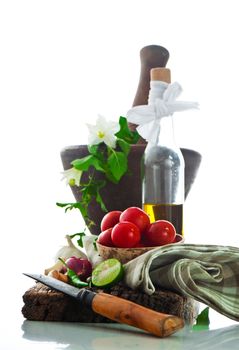 fresh vegetables and olive oil on an old weathered wood with a old mortar in behind over white background