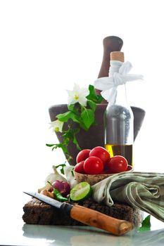 fresh vegetables and olive oil on an old weathered wood with a old mortar in behind over white background