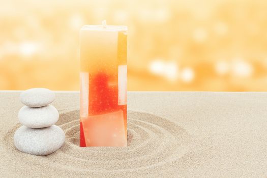 Balance zen stones and candle in sand on bokeh background