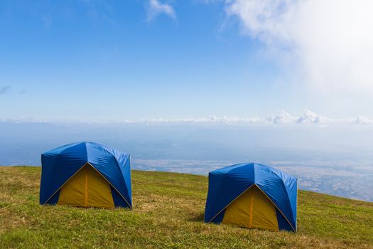 Two Tent on a grass under white clouds and blue sky
