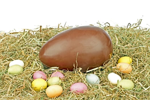 Chocolate egg with little colored eggs in straw