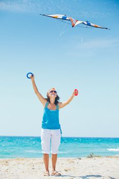 Young cute woman playing with a colorful kite on the tropical beach. Vertikal veiw