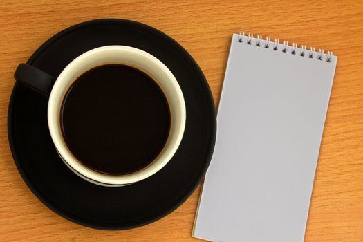 Coffee cup and white notebook