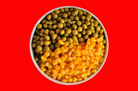 a plate with corn and peas, isolated, on a red background