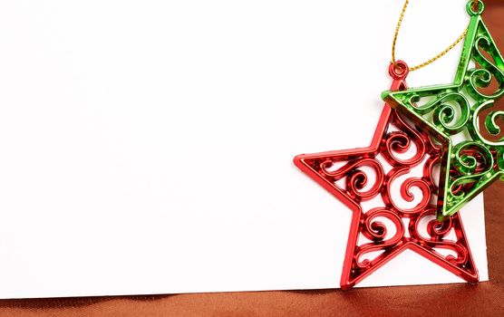 Two Christmas star decorations and white card with copy space. 