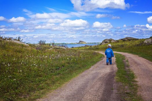 little baby boy walking country road