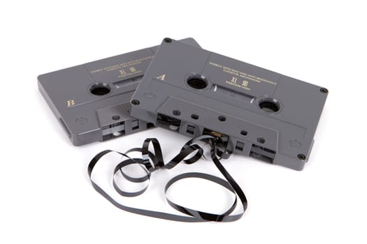 Obsolete magnetic audio cassette tapes partially unwound on a white background.