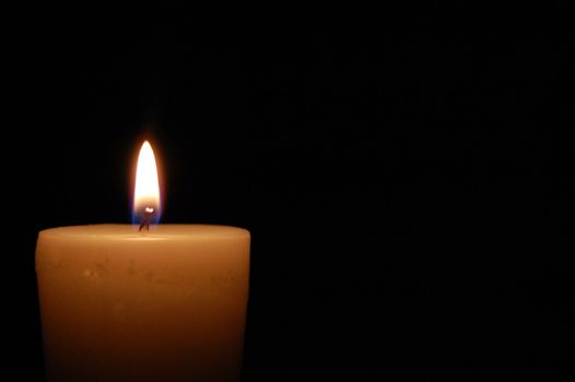 Single candle glowing in the dark (also space for text)