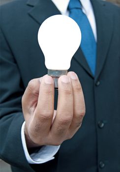 Man with a suit and tie holding a lit bulb