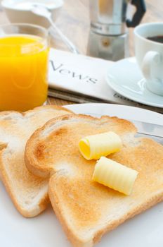 Butter on toast with coffee and newspaper in the background