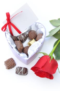 Assortment of chocolates inside a heartshaped box with a red rose