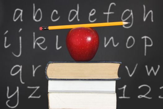 Pencil balancing on an apple and a stack of books