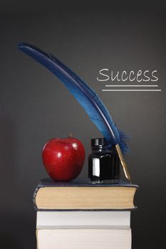 Stack of books and an apple next to a blank blackboard