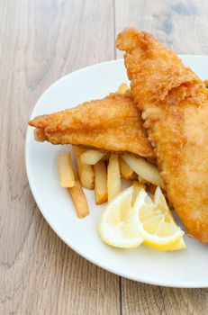 Side view of a plate of fried fish fillets with chips 