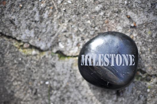 Pebble stone engraved with the word milestone