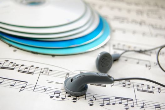 Pair of earphones on a music score with cds