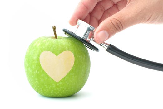 Hand holding stethoscope over an apple with a heart shape etched out in the middle 