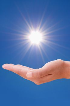 Hand holding the sun against a clear blue sky  