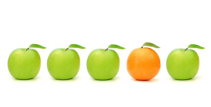 Orange stands out in a line of green apples
