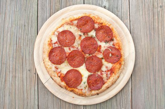 Freshly cooked pepperoni pizza on a round wooden board