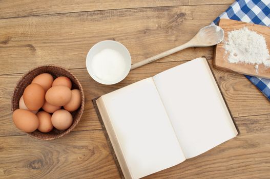 Open blank recipe book surrounded with ingredients 