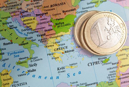 One euro coins next to a map of Greece