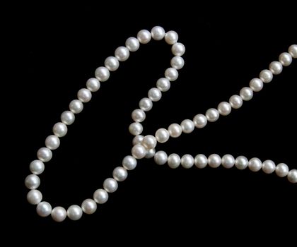 White pearls on the black velvet background 