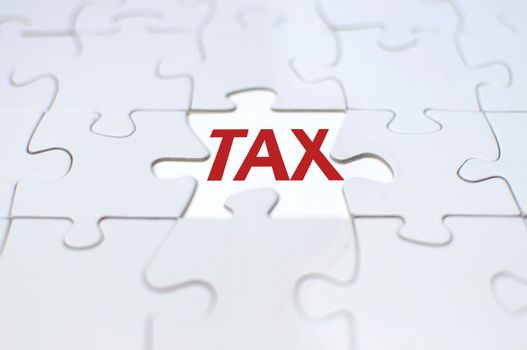 Missing piece from a jigsaw puzzle revealing the word tax 