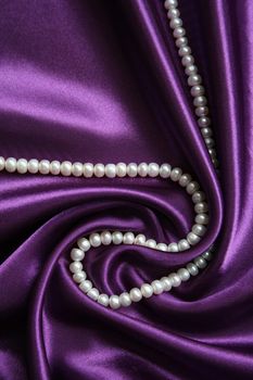 White pearls on a lilac silk as background 