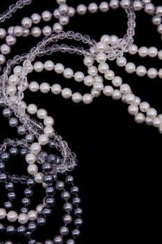 White, black and grey pearls on the black silk background 