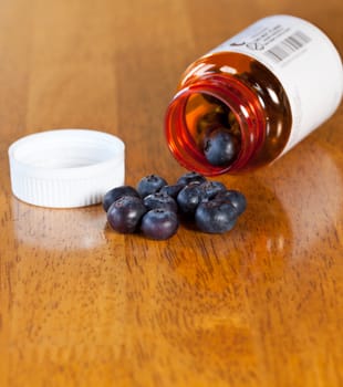 Fresh blueberries being poured from orange prescription bottle onto wooden table for breakfast