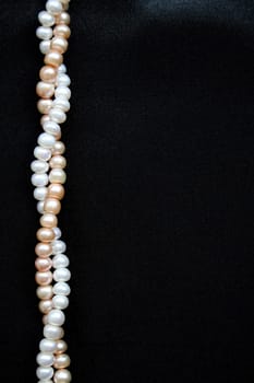 White and pink pearls on the black silk can use as background
