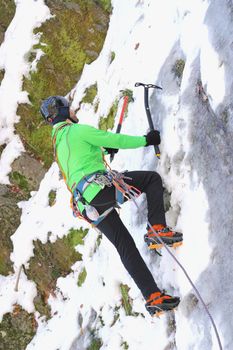 man in green jumper climbing an ice wall 