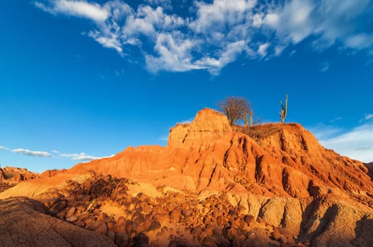 Red hill in a desert with large rocks scattered around the base in Huila, Colombia