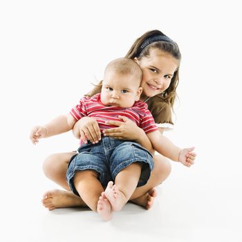 Cute little hispanic girl holding baby brother in her lap.