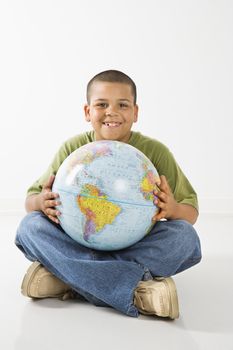 Young latino adolescent boy sitting with globe.
