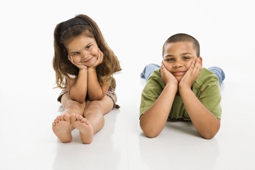 Hispanic brother and sister sitting smiling at viewer.