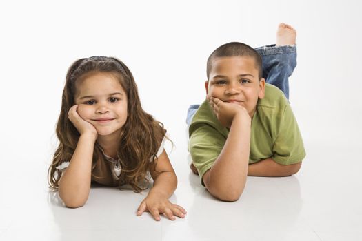 Portrait of Hispanic brother and sister lying on floor smiling at viewer.