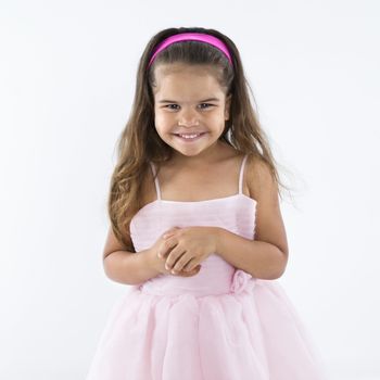 Cute little hispanic girl wearing pink dress smiling.
