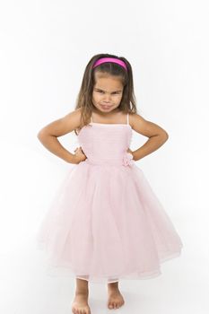 Little hispanic girl wearing pink dress pouting at viewer.